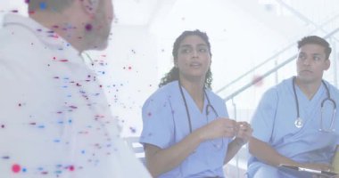 Klinisyen, hastane merdivenlerinde iş arkadaşları başını sallarken steteskopla işaret etmeye başladı. Tıbbi ekip, işbirliği, iletişim, profesyonel, sağlık, tartışma, çeşitlilik