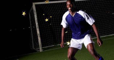 Kaleci yükselen savunma kalesi, kayan altın yıldızlarla spora girerken futbol topuna öncülük ediyor. Atletik, aksiyon, dinamik, gece vakti, kutlama, rekabetçi, kararlı