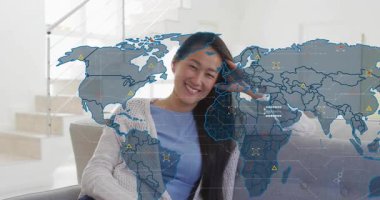 Dünya haritası, teknoloji veri akışını temsil eden ikonlarla örtüşürken dinlenme odasında gülümseyen bir kadın. Yenilik, bağlantı, teknoloji, dijital, iletişim, küreselleşme, analitik