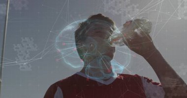 Dışarıdaki tarlada kırmızı forma giyen genç çocuk, sinirsel kaplamalı su şişesinden su içiyor. Sporcu, ferahlatıcı, teknoloji, yenilik, canlılık, açık hava, spor