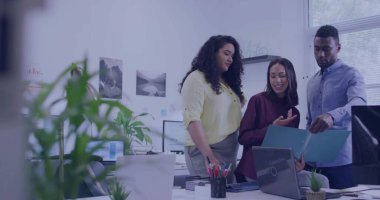 Modern ofis beyaz masasında dizüstü bilgisayarı ve mavi klasörlü belgeleri inceleyen üç profesyonel. İşbirliği, takım çalışması, şirket, çalışma alanı, teknoloji, iletişim, üretkenlik