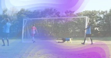 Kırmızı saldırgan gol atmak için futbol topuna vuruyor. Kaleci dalışı yapıyor ve takımlar yeniden toplanıyor. Eylem, rekabet, takım çalışması, açık hava, spor, enerji, dinamik