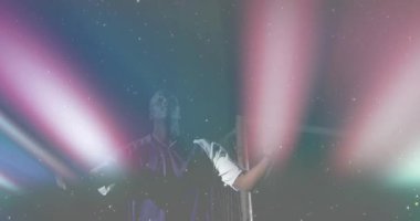 Renkli kirişlerin yer aldığı spor tanıtımı. Kollarını kaldıran, kalenin etrafında parıldayan bir sporcu. Dinamik, atletik, aydınlatma, performans, enerjik, gece manzarası, canlı