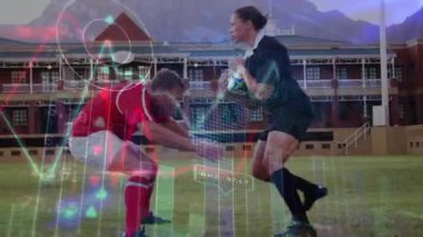 Top taşıyıcı ilerliyor, defans oyuncusu spor grafiği örtüsüyle ilerlemeyi durdurmak için çömeliyor ve mücadele ediyor. Atletizm, rekabet, çeviklik, stadyum, takım çalışması, strateji, hareket