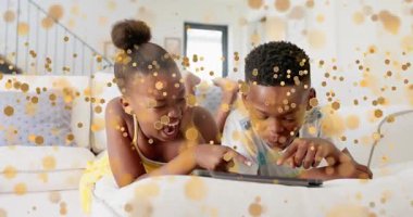 Kardeşler beyaz kanepede yatıp tableti göstererek altın kıvılcımlar saçarak teknik demo için sürükleniyorlar. Aile, arkadaşlık, eğlence, modern, eğlenceli, bağlantı, neşeli