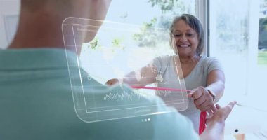 Antrenör kavramayı ayarlıyor. Kırmızı bant çeken ve holografik finans grafiklerini izleyen bir kadın. Fitness, sağlık, dijital sağlık, kıdemli bakım, kuvvet eğitimi, yenilikçi teknoloji