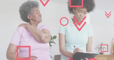 Üst düzey bir hasta, omuzlarını ovuyor, sağlık hizmetlerinde ağrıyı açıklıyor, hasta bakıcısı not alıyor, pano yansıması yapıyor. Sağlık, empati, iletişim, sağlık, destek, şefkat, danışma