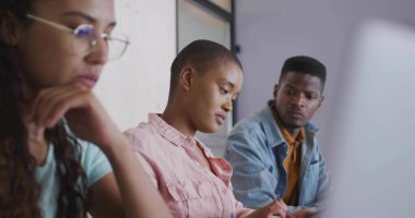 Pembe düğmeli gömlekli bir kadın çalışma odasında not alıyor, dizüstü bilgisayarla. İşbirliği, takım çalışması, öğrenme, eğitim, iletişim, modern, yaratıcı