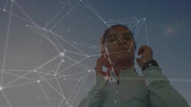 Kırmızı kulaklıkları takan kadın ve fermuar ceketi spor için ışıldayan ağ örtüsünü etkinleştirirken. Fitness, technology, wellness, innovation, athletic, motivasyon, activewear