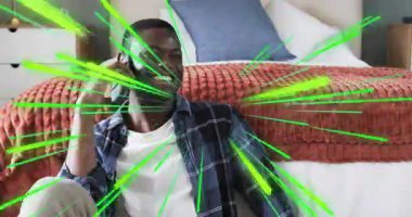 Yataktaki adam telefona cevap veriyor. Çevresindeki yeşil hatları aktifleştiriyor. Teknolojide tepki gösteriyor. İletişim, bağlantı, rahatlama, dijital, ruh hali, mutluluk, modern