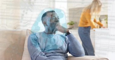 Kanepede oturan bir adam çerçeveye giriyor, teknoloji altıgen ağı animasyonu yaparken sırtına sarılıyor. Yakınlık, şefkat, bağlantı, modern, yaşam tarzı, teknoloji, sıcaklık