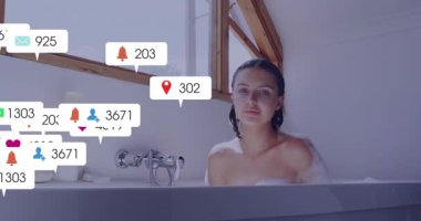 Yetişkin bir kadın köpük banyosuna yerleşiyor, aşırı yüklenme gösteren sosyal medya simgelerini başlatıyor. Rahatlama, bencillik, sağlık, kaplıca, hapsetme, farkındalık, sükunet