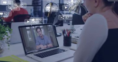 Ofis çalışanı dizüstü bilgisayarda uzaktan konuşma yapıyor ve yüzen sosyal medya nişan simgelerini izliyor. İşbirliği, üretkenlik, dijital, iletişim, modern, teknoloji, çalışma alanı