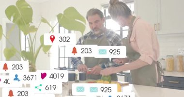 Tezgahta sebze doğrayan ve sosyal medya uyarıları ekleyen ve nişanı yükselten bir çift. Mutfak, takım çalışması, modern, taze, etkileşim, teknoloji, sağlık