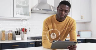 Man leaning on white counter propping tablet tapping content while exploring technology icons. Digital, connectivity, modern, innovation, communication, smart, wearable