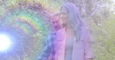 Kadın, güneşli bahçe yolunda yürüyor ve erkek, sağlık pazarlamasında sevgi dolu kucaklaşmayı paylaşıyor. Bahçe, arkadaşlık, açık hava, dinginlik, şefkat, olgunluk, uyum.