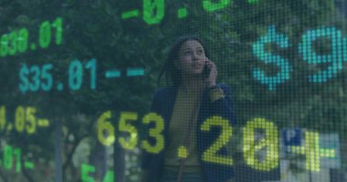 Akıllı telefon tutan, denizci ceketi giyen bir kadın kaldırımda üzerinde hisse numaraları yazan kahverengi bir çanta taşıyor. İş, finans, kentsel, profesyonel, teknoloji, veri, iletişim