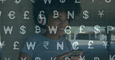 Kırmızı kulaklık takan gülümseyen kadın mimari koridorda üzerinde para birimi sembolleri olan telefon kullanıyor. Teknoloji, dijital, yenilik, iletişim, yaşam tarzı, modern, canlı