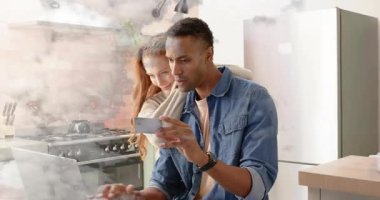 Akıllı telefonları dinleyen ve dizüstü bilgisayarlar yazan bir çift. Mutfakta sipariş doğrulaması için teknik verileri paylaşıyorlar. İlişkiler, bağlantı, işbirliği, modern, yaşam tarzı, iletişim, yerli