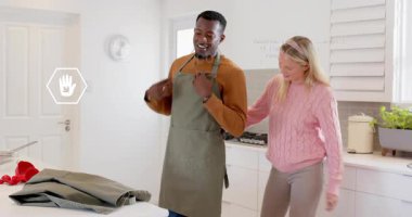 Kadın zeytin yeşili önlük seçiyor ve eşe veriyor. Çiftler yemek değiştirip hazırlanıyor. Yurt içi, hazırlık, işbirliği, yaşam tarzı, konfor, uyum, gündelik