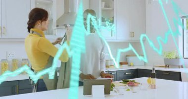 Kadın, erkeklerin tablete dokunması, yemek pişirmek için canlı dalgalarla doğraması ve kesmesi üzerine önlük örtüyor. Yemek pişirme, takım çalışması, modern, yaşam tarzı, sağlıklı, işbirliği, canlı