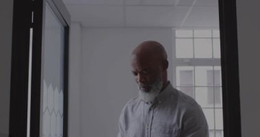 Man pulling phone from pocket scrolling as code overlaying glass partition confirming tech status. Professional, technology, sleek, futuristic, innovation, workspace, digital
