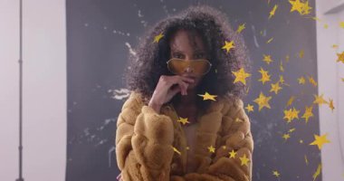 Güneş gözlüğü kaldıran, işaret eden, altın yıldızlı moda çekimi için saç şekillendiren bir kadın. Göz makyajı, cazibe, güven, tarz, zarafet, stüdyo, kampanya