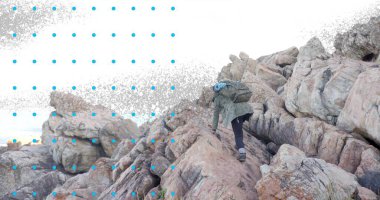 Yeşil ceketli yetişkin bir yürüyüşçü okyanusun yanındaki kayalara tırmanıyor mavi sırt çantalı, kopya alanı. Macera, keşif, açık hava, engebeli, yalınayak, kıyı şeridi, vahşi doğa.