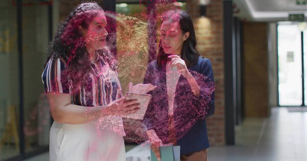 Two colleagues projecting pink digital holograms in office corridor, with tablet, pastel folder. Technology, innovation, collaboration, professionalism, futuristic, corporate, digital