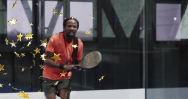 Adam yeşil topa raket sahasında tepki veriyor, altın yıldızlı atışla geri dönüyor ve salıncakları vurguluyor. Atletik, dinamik, enerjik, enerjik, canlı, rekabet, boş zaman, spor