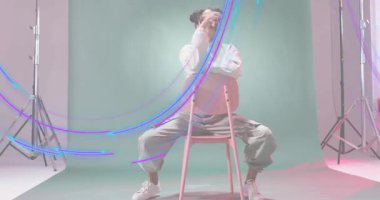 Moda modeli, dönen hafif aksaklık etkilerine tepki veren bir sandalyede oturuyor. Moda, moda, portre, stüdyo, çağdaş, minimalist, canlı