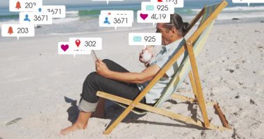 İçkisini yudumlayan, plajda tablet kullanan sosyal medya uyarıları üreten bir adam. Rahatlama, rahatlama, teknoloji, iletişim, açık hava, huzur, refah