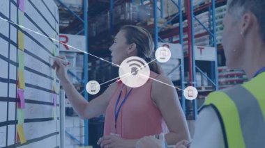 Lojistik planlayıcısı, gerçek zamanlı veri akışını gösteren ağ oluşturma kaplamasına yapışkan notlar yazıyor. İşbirliği, takım çalışması, lojistik, planlama, veri görselleştirme, iş akışı, depo