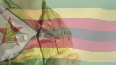 Kamuflajlı adam kavramayı ayarlıyor, kameralar zumluyor Zimbabve bayrağıyla çözümü gösteriyor. Vatanseverlik, askeri, güvenlik, güç, adanmışlık, kararlılık, esneklik