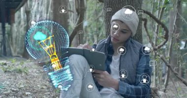 Ağaca vurma tabletine yaslanan bir adam yanıp sönen ampullü ikonlar üretiyor. Yenilik, yaratıcılık, teknoloji, doğa, beyin fırtınası, farkındalık, dijital