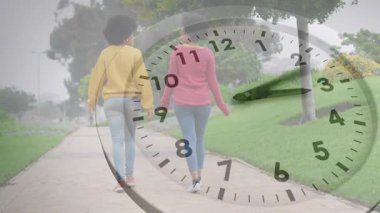 Yürüyen iki kadın saat, iş için zaman geçidini belirlemek için el işaretlerini değiştiriyor. Arkadaşlık, açık hava, gündelik, boş zaman, zamansız, uyum, yenilenme