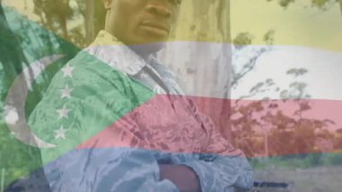 Asker, savunma eğitimi sırasında komuta değişimi pozu alıyor ve animasyon ikonuyla gülümsüyor. Ordu, açık hava, kamuflaj, orman, esneklik, disiplin, liderlik.