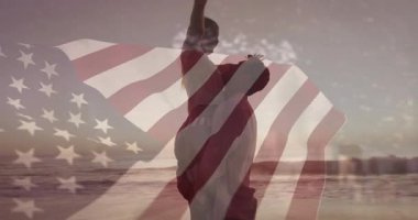 Erkek, gün batımı kumsalında kadını kaldırıyor, kutlama için döndürüyor, Amerikan bayrağını örtüyor. Romantik, kutlama, birlik, özgürlük, zarafet, uyum, alacakaranlık