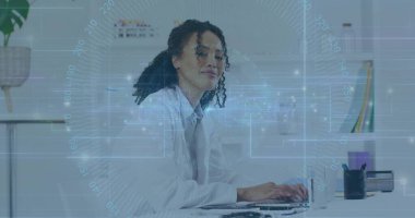 Ofis masasında laboratuvar önlüğü giyen bir bilim adamı dizüstü bilgisayar ve kupa kullanıyor. Profesyonel, yenilikçi, modern, çalışma alanı, üretkenlik, işbirliği, teknoloji