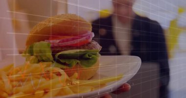 Hamburger ve patates kızartması sunucu, yemeğe odaklanıyor, ızgaralar zayıflıyor ve finans grafikleri yükseliyor. Günlük yemek, iş yemeği, dijital analiz, işyeri kültürü, modern çevre