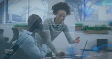 İş arkadaşı masanın üzerine eğilip dizüstü bilgisayarı göstererek doktoru inceleyen ve işbirliği yapan adamı tetikliyor. İşbirliği, takım çalışması, profesyonel iletişim, beyin fırtınası, üretkenlik, modern