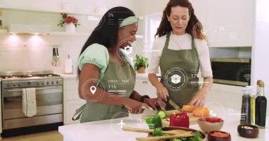 Salata için salatalık ve biber dilimleyen iki kadın. Çevrelerinde dijital ikonlar yanıp sönerken. İşbirliği, aşçılık, modern, sağlıklı, yaşam tarzı, hayat dolu, takım çalışması