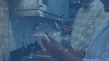 Sebzeler doğranıp sotelenirken kıdemli çift yemek tarifini animasyonlarla birlikte tablette kullanıyor. Aşçılık, işbirliği, modern mutfak, aşçılık, eğlence, yaşam tarzı, teknoloji