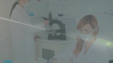 Lens temizliği bilim adamının laboratuvar mikroskobunu ayarlamasına ve meslektaşının şişe örneğini incelemesine neden oluyor. Araştırma, takım çalışması, yenilik, deney, bilimsel, profesyonel, modern