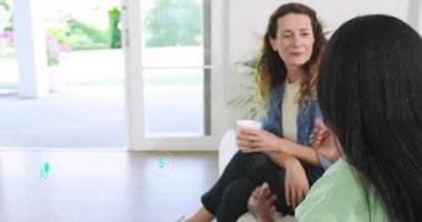 Oturma odasında akıllı telefon uygulamasını dinleyen ve animasyon finans sağlığı enerji ikonlarını ortaya çıkaran iki kadın. Dostça sohbet, modern yaşam tarzı, bağlantı, rahatlama, iletişim