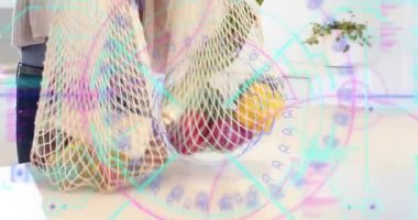 Kadın tezgahın üzerine ağ torbaları yerleştiriyor, besleyici bilgiler gösteren canlı etiketli sebzeleri açıyor. Organik, sürdürülebilir, çevre dostu, minimalist, taze ürün, gıda hazırlama, modern mutfak