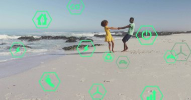 Dönen çift su kenarında kumlu sahilde el ele tutuşuyor. Dağınık kayalar ve ayak izleri var. Romantizm, eğlence, uyum, dinginlik, açık hava, yaşam tarzı, canlı