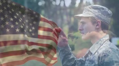 Hava kuvvetleri mensubu, bayrağın rüzgarda dalgalanması ve saygı göstermesi üzerine el kaldırıyor. Askeri, vatanseverlik, disiplin, cesaret, açık hava, doğa, ciddiyet