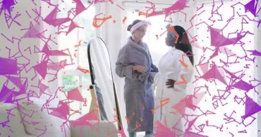 Gri cüppeli kadın kavanoza uzanıyor ve arkadaşının yanağına krem sürüyor, spa rutinini gösteriyor. Sağlık, rahatlama, dostluk, cilt bakımı, samimiyet, samimiyet.