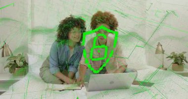 Dizüstü bilgisayarda yazan ve telefonlarını dinleyen iki kadın güvenlik ızgarasını ateşleyip asma kilit oluşturarak veri topluyor. İşbirliği, dostluk, teknoloji, dijital güvenlik, çalışma alanı, modern, yenilik